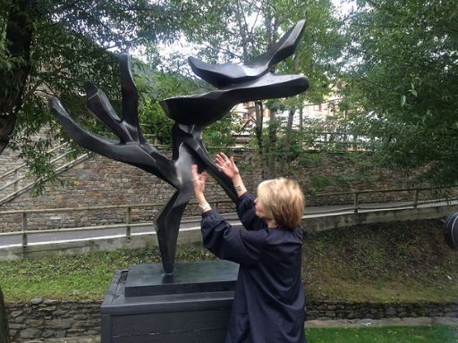 Hedva Ser, UNESCO Artist for Peace, is seen interacting with her iconic sculpture, Tree of Peace, in an outdoor setting surrounded by greenery